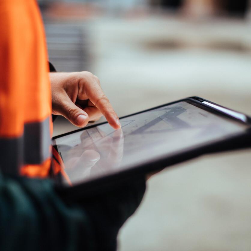 man holding tablet with plans on it